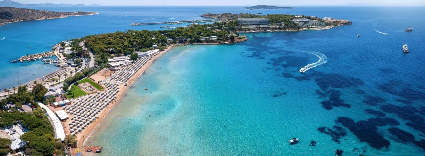 Aerial view of the famous luxury beach Astir in south Athens, bay of Vouliagmeni, Greece, with water sports over turquoise sea
